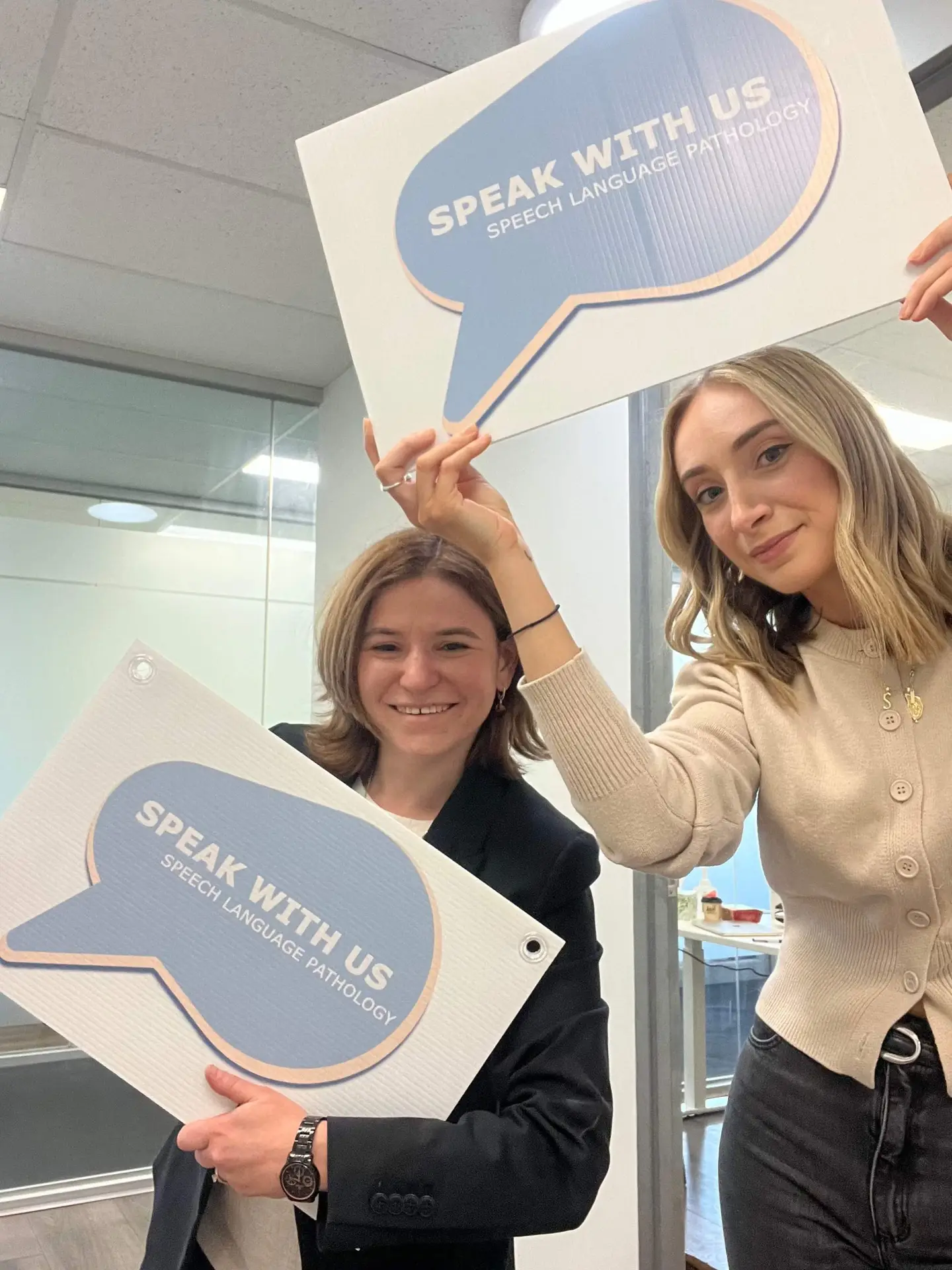 The Speak With Us team holding speech bubble signs